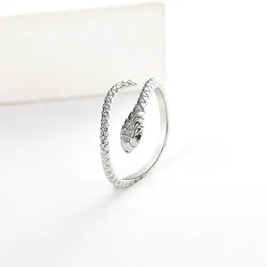 Macro detail of silver snake ring featuring green gemstone eyes and micro-set crystals