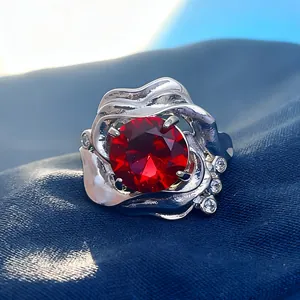 Silver ring featuring a large round red gemstone with claw setting on blue silk
