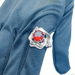 Detail of silver asymmetric ring with a large round red gemstone on a gloved hand