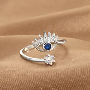Macro shot of silver evil eye ring with blue stone and star on brown satin