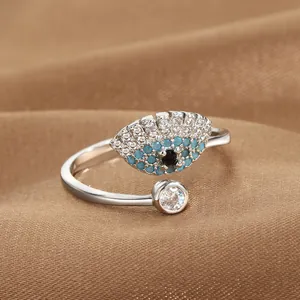 Macro shot of silver evil eye open ring featuring blue zircon inlay on brown fabric