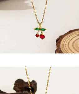Detail of elegant cherry pendant necklace with red and green gemstones on gold chain
