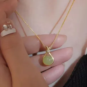 Collana sacchetto della fortuna dorata con ciondolo in giada verde sul collo