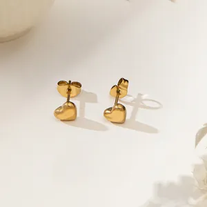 Boucles d'oreilles cœur en plaqué or 18 carats pour femme sur fond minimaliste épuré