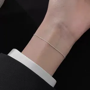 Detailed view of a sleek silver snake chain bracelet paired with a professional suit cuff
