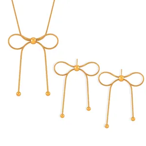 Detail of gold bow jewelry set with snake chain necklace and matching stud earrings