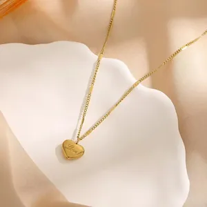 Detail view of a polished gold heart pendant with Love engraving on a silk background