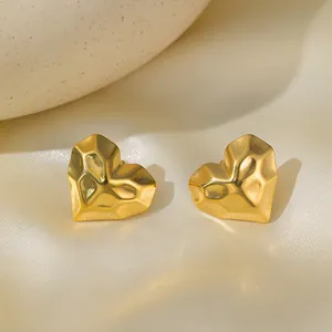 Dettaglio di orecchini a cuore placcati oro 18K con texture sfaccettata su seta