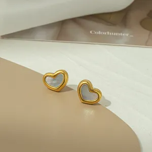 Dettaglio macro di orecchini a cuore con bordi dorati e inserto in madreperla cangiante