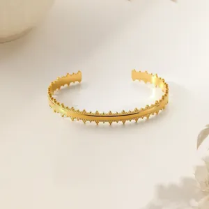 Detailed shot of gold-plated open knot bangle with intricate crown-textured edges