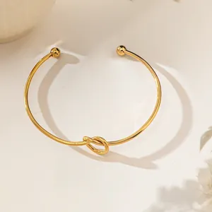 Detailed close-up of 18K gold plated knotted open bangle with elegant ball end caps