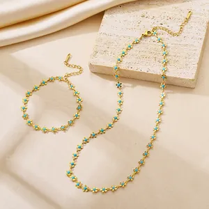 Detailed close-up of golden titanium necklace and bracelet set with blue daisy charms