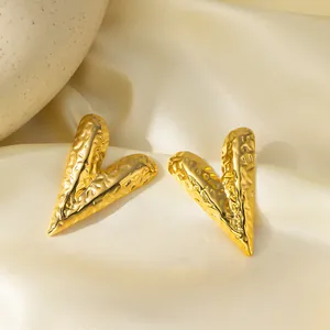Detail of 18K gold plated heart earrings with a unique hammered texture on silk fabric