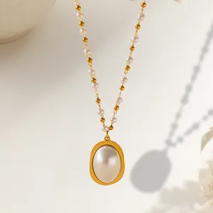 Detail of elegant gold necklace featuring fine metal beads and large oval pearl pendant