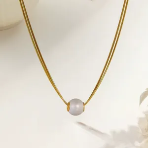 Detail of a large purple pearl pendant on a sleek golden snake chain necklace