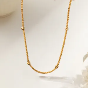 Detail of gold plated stainless steel star chain with polished beads on white background
