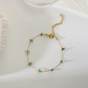 Dettaglio del bracciale dorato con pietre verdi irregolari e chiusura a moschettone