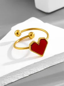 Macro shot of gold open heart ring with red enamel and beaded edge detail