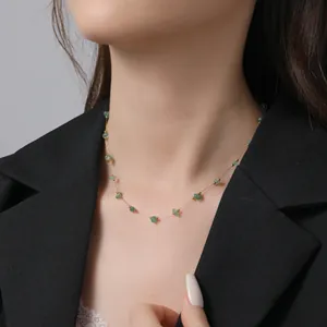 Dettaglio di una collana placcata oro con pietre verde chiaro indossata da modella