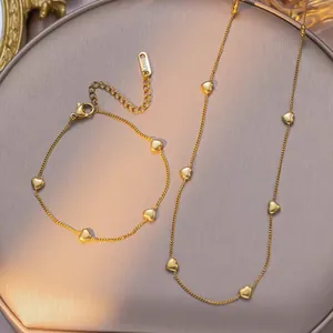 Detail of gold heart pendant necklace and bracelet set with S.STEEL engraved tag