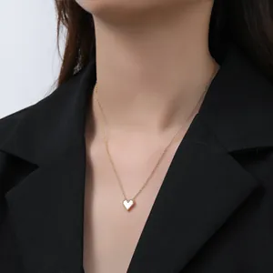 Close-up of gold heart pendant necklace with white mother-of-pearl inlay on a model