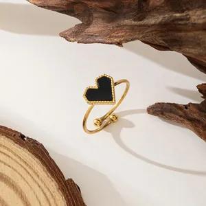 Detailed close-up of a golden heart ring featuring black enamel and beaded trim edges