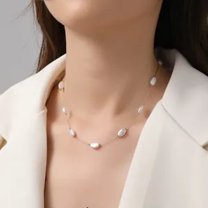 Barockperlenkette mit Goldkette, getragen von einem Modell in weißem Blazer