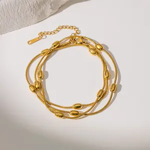 Detail of layered gold snake chain necklace with polished beads and lobster clasp