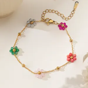 Makroaufnahme eines goldenen Edelstahl-Armbands mit fünf bunten perlenbesetzten Blumen