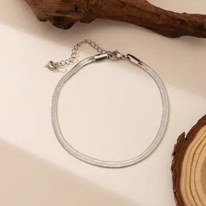 Elegant silver snake chain bracelet in titanium steel on a natural wood background
