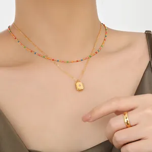 Detail of double-layer gold necklace with square pendant and diamond texture ring