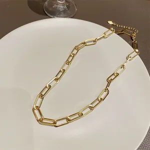 Detailansicht einer goldenen Büroklammer-Halskette auf einem weißen Keramiktablett