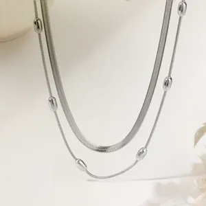 Detail of silver layered necklace with snake chain and polished beads on beige background