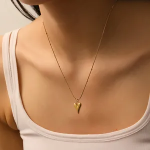 Close-up of a 18k gold plated solid heart pendant necklace on a bead chain shown on a model