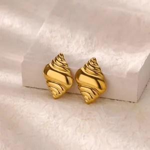 Golden conch shell stud earrings in matte stainless steel on white stone display