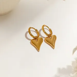Orecchini a cuore in oro lucido con chiusura rotonda su sfondo minimalista raffinato