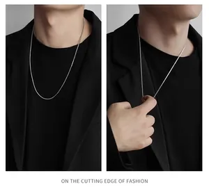 Detailweergave van de zilveren vierkante slangenketting op het model en in de hand