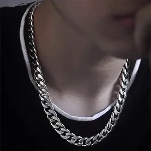 Close-up van gepolijste zilveren Cubaanse schakelketting gedragen op casual kleding