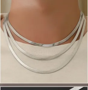 Close-up of three layered silver stainless steel herringbone snake chains on model