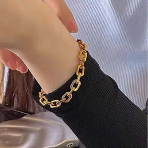 Detailansicht eines goldfarbenen Gliederkettenarmbands getragen am Handgelenk eines Models
