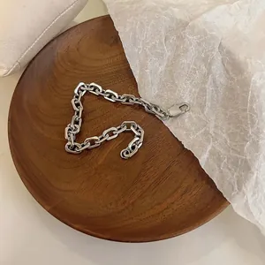 Minimalistisches Gliederketten-Armband in Silber mit Karabinerverschluss auf Holztablett