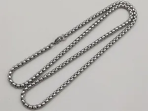 Macro detail of silver stainless steel box chain necklace with a secure lobster clasp