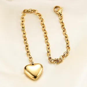Polished gold heart pendant on a thick rolo chain over champagne silk background