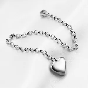 Detailed close-up of a silver heart charm bracelet on white silk with polished finish