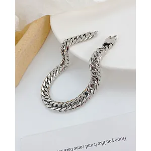 Macro detail of silver Cuban link chain bracelet with a heavy lobster clasp closure