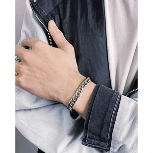 Close-up of polished silver stainless steel Cuban link bracelet on a male wrist
