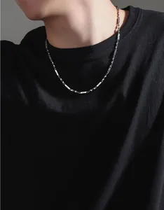 Dettaglio della collana in acciaio al titanio su un modello con t-shirt nera