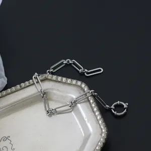 Poliertes Silber-Büroklammer-Armband mit Federverschluss auf Vintage-Tablett