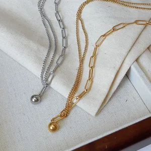 Detalle del collar de cadena cubana chapado en oro de 18K y plata con colgante de bola