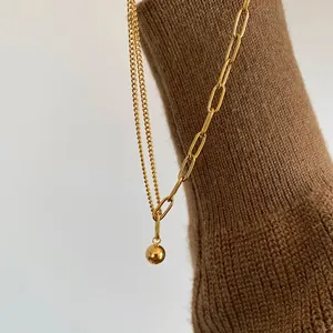 Detalle del collar de doble capa chapado en oro de 18K con colgante de bola y eslabón